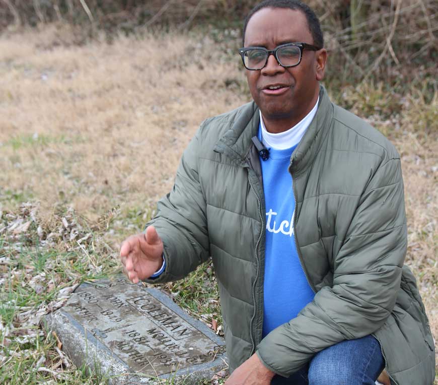 Coleman kneels at the gravestone of his great-grandparents